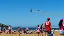 Para pengunjung pantai saat menyaksikan aksi tim aerobatik Angkatan Udara Spanyol, Patrulla Aspa yang bermanuver menggunakan helikopter di San Lorenzo, Gijon, Spanyol, Minggu (24/7). (REUTERS/Eloy Alonso)