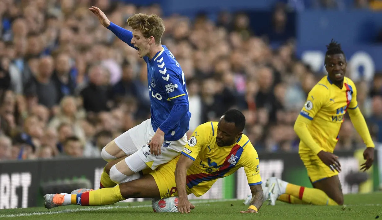 <p>Striker Crystal Palace Jordan Ayew (tengah) menjegal striker Everton Anthony Gordon (kiri) pada laga tunda pekan ke-33 Liga Inggris di Goodison Park, Jumat (20/5/2022) dini hari WIB. Everton dipastikan selamat dari zona degradasi usai menang dramatis 3-2 atas Crystal Palace. (Oli SCARFF / AFP)</p>