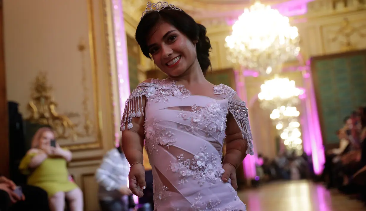 Model berpose di atas catwalk ketika menampilkan gaun khusus perempuan bertubuh pendek dalam International Dwarf Fashion Show di Paris, Selasa (26/9). Para model dengan tinggi maksimal 1,3 meter ini memukau para penonton yang hadir (Thomas SAMSON/AFP)