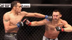 Tony Ferguson (kiri) melakukan pukulan tangan kiri ke Michael Chandler pada pertarungan kelas ringan putra UFC 274 di Footprint Center, Phoenix, Arizona, Amerika Serikat, 7 Mei 2022. Chandler dinyatakan menang KO atas Ferguson. (Christian Petersen/Getty Images/AFP)