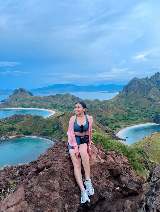 Prilly mendaki bukit di Labuan Bajo kenakan active wear. Berwarna hijau, active wear yang dikenakan Prilly terdiri dari sport bra dan legging pendek senada. Ia melapisinya dengan jaket parasut berwarna merah muda. Foto: Instagram.