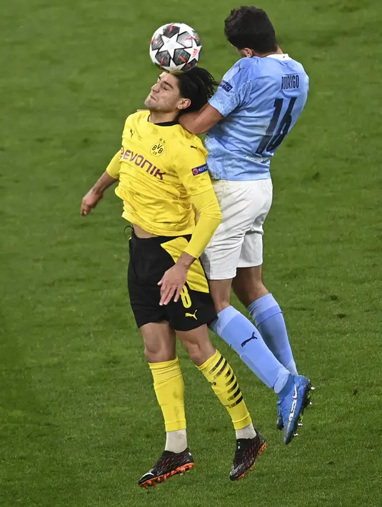 Gelandang Manchester City, Rodrigo berebut bola udara dengan gelandang Borrusia Dortmund, Mahmoud Dahoud pada pertandingan leg kedua perempat final Liga Champions di stadion Signal Iduna Park, Jerman (15/4/2021). The Citizens unggul agregat 4-2 atas Dortmund. (Federico Gambarini/Pool via AP)