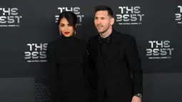 Pemain Paris Saint-Germain asal Argentina, Lionel Messi (kanan) dan istrinya Antonela Roccuzzo berpose setibanya pada acara The Best FIFA Football Awards 2022 di Paris, Prancis, 27 Februari 2023. Messi yang mengenakan setelan jas serba hitam tampak serasi dengan Antonella dengan gaun warna senada. (FRANCK FIFE/AFP)