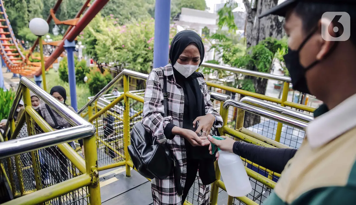 Petugas menyemprotkan cairan disinfektan kepada pengunjung yang akan menaiki wahana bermain di Dunia Fantasi, Ancol, Jakarta, Minggu (10/10/2021). Pelonggaran PPKM level 3 di Jakarta membuat sejumlah tempat wisata kembali ramai didatangi pengunjung. (Liputan6.com/Faizal Fanani)