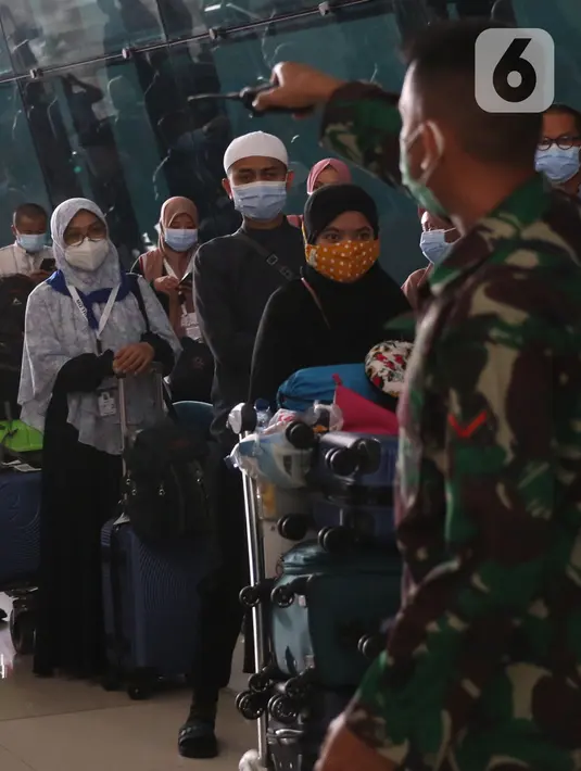 Petugas mengatur rombongan jemaah umrah setibanya mereka di Bandara Soekarno Hatta, Tangerang, Selasa (29/12/2020). Rombongan jemaah umrah yang baru tiba di Indonesia tersebut diarahkan untuk melakukan karantina di tempat yang telah disediakan oleh pemerintah. (Liputan6.com/Angga Yuniar)