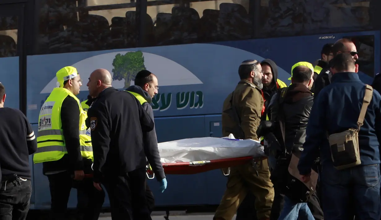 Petugas mengevakuasi jenazah dari lokasi serangan truk yang menabrak sejumlah tentara Israel di sebuah tempat wisata di Yerusalem, Minggu (8/1). Polisi setempat mengatakan tiga dari empat korban tewas adalah perempuan. (AP Photo/Mahmoud Illean)