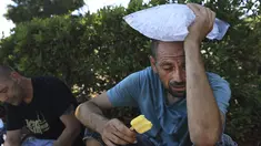 Michael Williams mendinginkan diri dengan es loli dan sekantong es saat suhu di Santa Rosa, California, naik 112 derajat, Senin, 5 September 2022. Barang-barang tersebut disumbangkan oleh sekelompok anggota komunitas di Santa Rosa. (Kent Porter/The Press Democrat via AP)