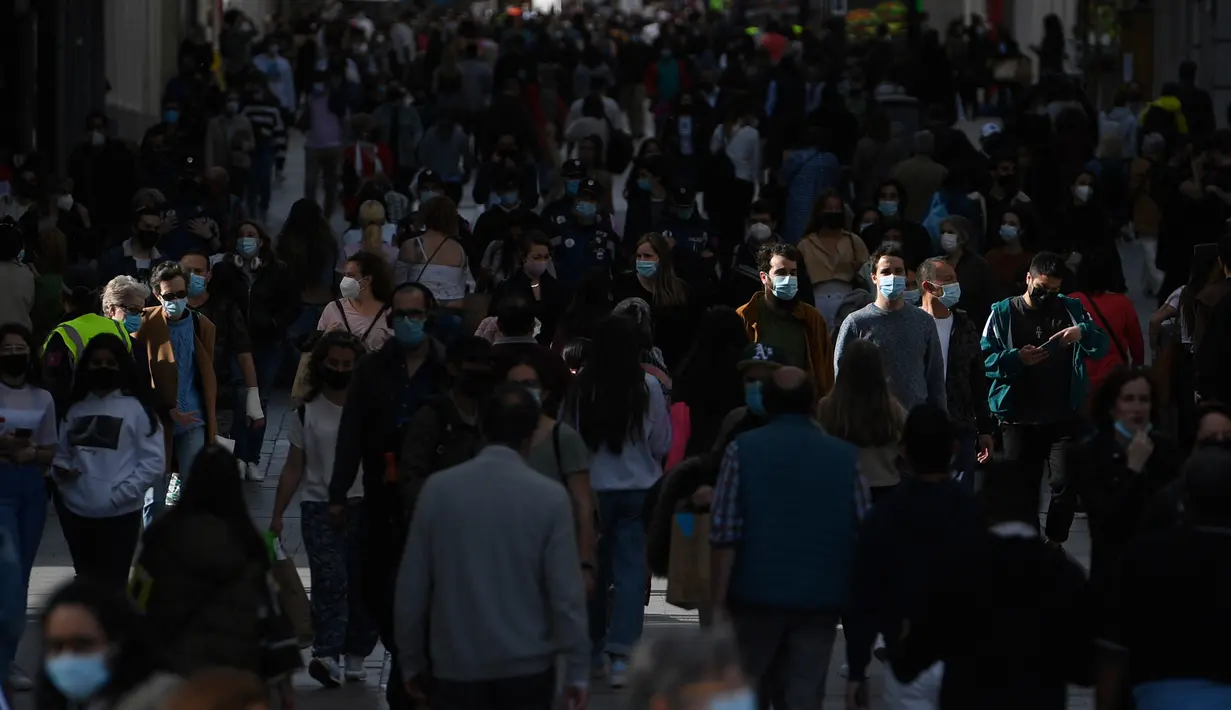 Orang-orang yang memakai masker berjalan di jalan Preciados yang padat di Madrid, Spanyol pada Rabu (31/3/2021). Spanyol memperketat aturan penggunaan masker dengan mewajibkannya di luar ruangan dan seluruh fasilitas publik. (PIERRE-PHILIPPE MARCOU / AFP)