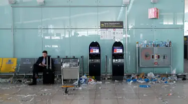 Seorang penumpang memainkan ponsel di antara sampah yang berserakan di Bandara Barcelona, Spanyol, Kamis (1/12). Para petugas kebersihan bandara tersebut menggelar aksi mogok kerja memprotes pengurangan anggaran sebesar 1,3 juta Euro. (REUTERS/Albert Gea)