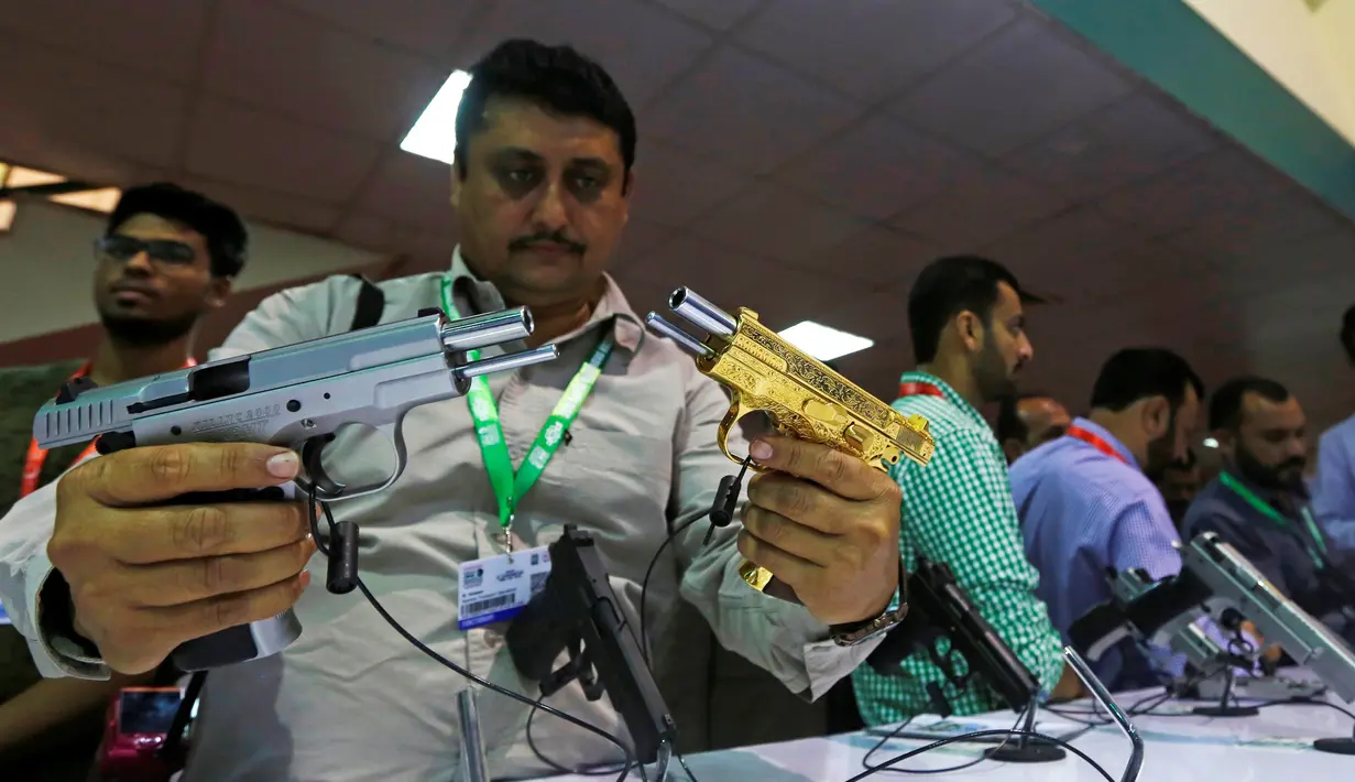 Seorang pengunjung membandingkan pistol saat Pameran Pertahanan Internasional dan Seminar "IDEAS 2016" di Karachi, Pakistan (23/11). Pameran alat tempur ini banyak diikuti oleh industri senjata dari berbagai negara. (Reuters/Akhtar Soomro)