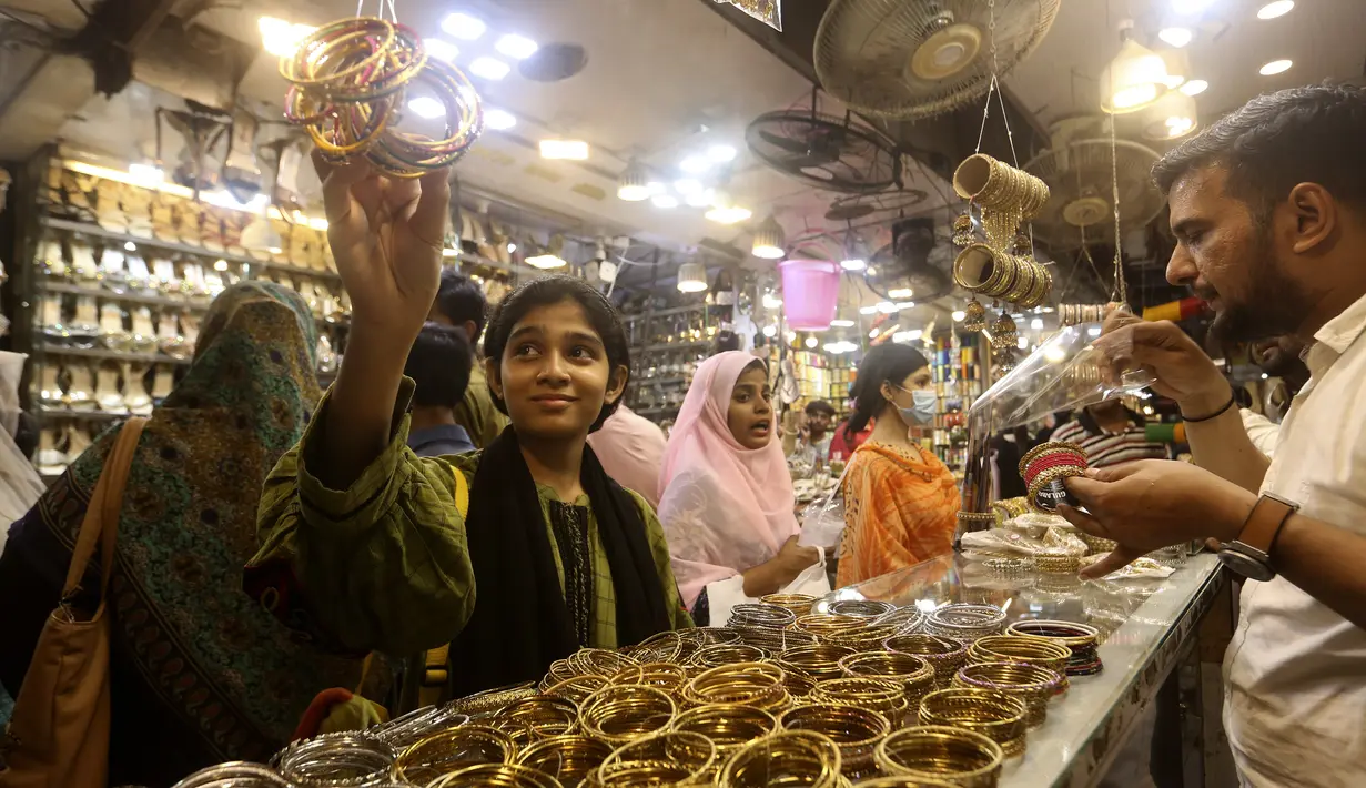 <p>Seorang gadis muda melihat-lihat gelang tradisional saat dia dan yang lainnya mengunjungi pasar untuk berbelanja perayaan Idul Fitri mendatang, di Karachi, Pakistan, Jumat, 29 April 2022. Idul Fitri menandai berakhirnya bulan suci Ramadhan.  (AP Photo/Fareed Khan)</p>
