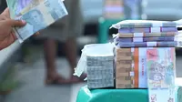 Penjual jasa penukaran uang pecahan menunggu konsumen di Jalan Otista Raya di Karawaci, Kota Tangerang, Senin (10/5/2021). Penjual jasa penukaran uang baru musiman tersebut mulai bermunculan menjelang lebaran yang dikenakan tarif jasa sebesar 10 persen. (Liputan6.com/Angga Yuniar)