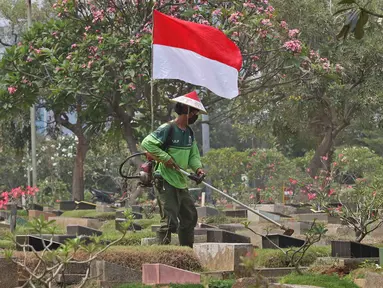 Petugas Pertamanan dan Kehutanan Kota Jakarta Pusat mengenakan atribut kemerdekaan saat memotong rumput di TPU Karet Bivak, Jakarta, Minggu (16/8/2020). Para petugas bekerja dengan mengenakan atribut kemerdekaan dalam rangka menyambut HUT ke-75 RI. (Liputan6.com/Herman Zakharia)