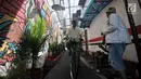 Pengendara sepeda melintas di depan lukisan tembok atau mural yang menghiasi gang di RT 13 RW 06, Jembatan Lima, Jakarta, Kamis (10/1). Warna-warni mural di pemukiman padat penduduk itu merupakan ide Aryanto selaku Ketua RT 13. (Merdeka.com/Iqbal Nugroho)