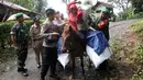 Polisi dan tentara membantu petugas Pemilu 2019 yang menaiki kuda untuk mendistribusikan logistik ke TPS di desa-desa terpencil di Tempurejo, Jawa Timur, Senin (15/4). Petugas membawa kotak suara dan perlengkapan pemilu lainnya. (AP Photo/Trisnadi)