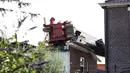 Salah satu mesin derek yang jatuh ke rumah warga di Alphen aan den Rijn, Belanda, Senin (3/8/2015) waktu setempat. Dua mesin derek yang sedang memperbaiki jembatan ambruk ke rumah yang ada di dekatnya dan melukai 20 orang. (AFP PHOTO/ANP/LEX VAN LIESHOUT)