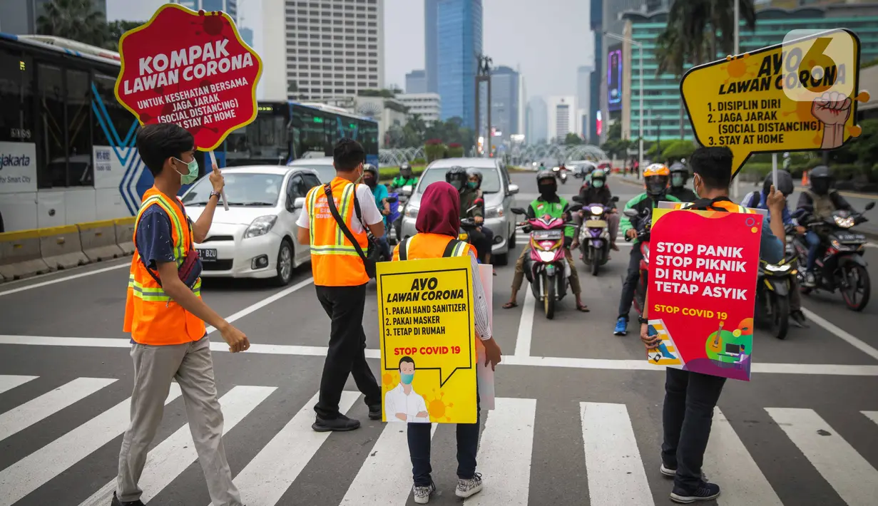 Relawan yang tergabung dalam Gerakan Mahasiswa Cegah Covid-19 membawa poster 'Ayo Lawan Corona' saat kampanye di Pelican Cross kawasan Thamrin, Jakarta, Senin (23/3/2020). (Liputan6.com/Faizal Fanani)