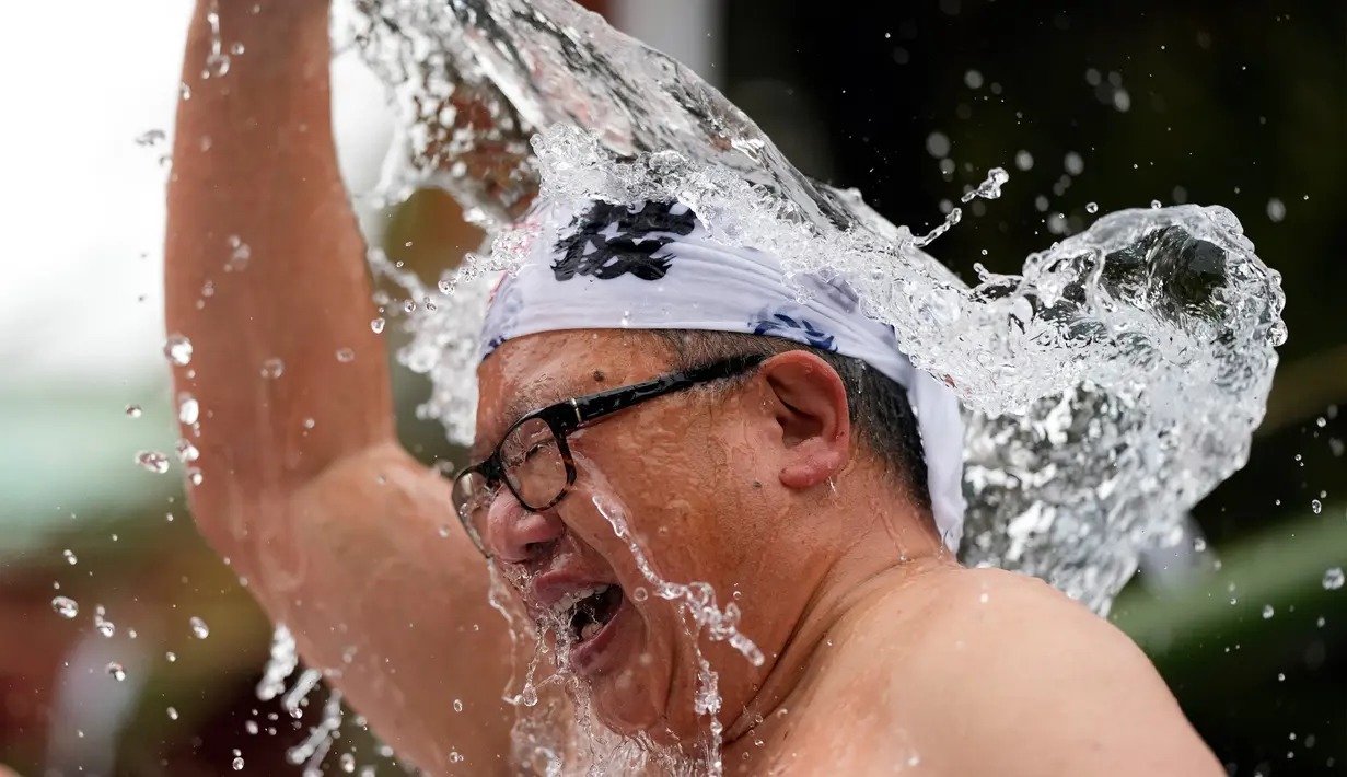 <p>Seorang jemaat yang setengah telanjang menyiram dirinya dengan air dingin saat ritual ketahanan dingin di Kuil Shinto Kanda Myojin, Tokyo, Jepang, Sabtu (14/1/2023). Dalam ritual yang berlangsung selama dua hari dan menjadi bagian dari festival Shinto itu peserta menuangkan air dingin ke tubuh karena diyakini dapat menyucikan jiwa mereka. (AP Photo/Hiro Komae)</p>