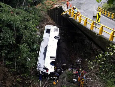 Petugas penyelamat melakukan evakuasi bus yang jatuh di jalan penghubung Medellin dan Bogota dekat San Luis, Provinsi Antiokia, Kolombia, 27 Desember 2021. Tujuh orang, termasuk seorang wanita hamil, tewas dan 20 lainnya luka-luka ketika sebuah bus terjun ke jurang. (Fredy BUILES/AFP)