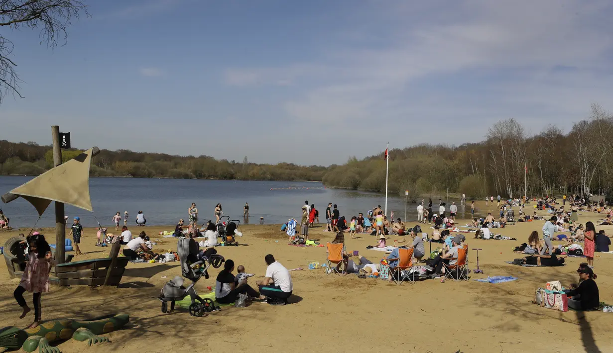 Orang-orang menikmati cuaca hangat di Ruislip Lido di London, Selasa (30/3/2021).  Suhu di beberapa bagian Inggris diperkirakan akan lebih hangat secara signifikan minggu ini karena keluarga dan teman berkumpul kembali dan kegiatan olahraga luar ruangan diizinkan untuk dilanjutkan di Inggris. (AP Ph