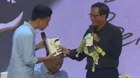 Momen lucu saat Mahfud MD tukeran kado dengan Gibran Rakabuming di acara Ulang Tahun Mata Najwa ke-13. (Dok: YouTube Mata Najwa)