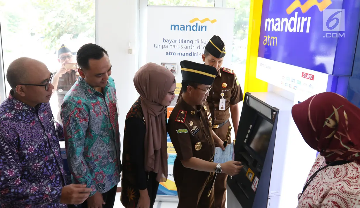 Kejati DKI Jakarta Tony T Spontana (kanan) melakukan transaksi pembayaran tilang online disaksikan SVP Hubungan Kelembagaan Bank Mandiri Dadang Ramadhan (kiri) di kantor Kejaksaan Negeri Jakarta Pusat, Jakarta, Kamis (3/1). (Liputan6.com/Angga Yuniar)