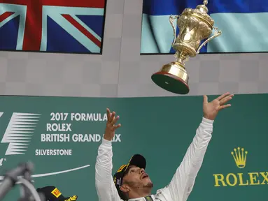 Pebalap Mercedes, Lewis Hamilton, melempar trofi usai menjuarai F1 GP Inggris di Sirkuit Silverstone, Minggu (16/7/2017). Pebalap 32 tahun asal Inggris itu melahap 51 lap dengan catatan waktu 1 jam 21 menit 27,430 detik. (EPA/Valdrin Xhemaj)