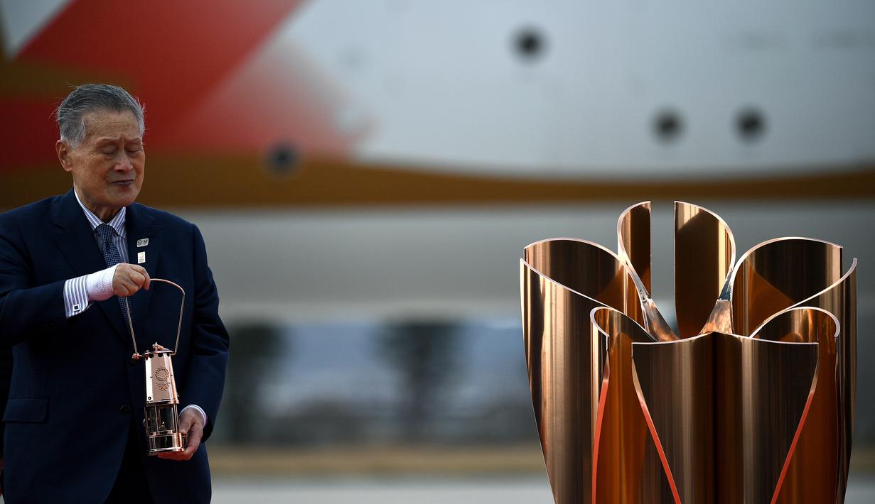 Presiden Olimpiade Tokyo 2020, Yoshiro Mori, membawa api untuk obor Olimpiade Tokyo 2020 saat tiba dari Yunani di Pangkalan Udara Matsushima, Jepang, Jumat (20/3). Di tengah pandemi virus corona Covid-19, prosesi menuju Olimpiade Tokyo 2020 masih terus berjalan. (AFP/Philip Fong)