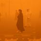 Pejalan kaki menyeberang jalan di tengah badai debu parah di Kota Kuwait pada 23 Mei 2022. Badai pasir telah melanda Timur Tengah dalam beberapa hari terakhir, dan menjadi fenomena yang para ahli peringatkan dapat berkembang luas karena perubahan iklim. (Yasser Al-Zayyat / AFP)