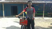 Sandi Setiawan di depan rumahnya dengan sepeda yang ia gunakan mudik. (KRJogja.com/Fatimah Arum)