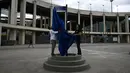 Orang-orang membuka tanda jalan bertuliskan "Avenue King Pele" di luar stadion Maracana di Rio de Janeiro, Brasil pada 4 Januari 2023. Balai Kota Rio de Janeiro secara resmi menamai jalan yang mengelilingi stadion Maracana Avenue Rei Pele (King Pele). (MAURO PIMENTEL/AFP)