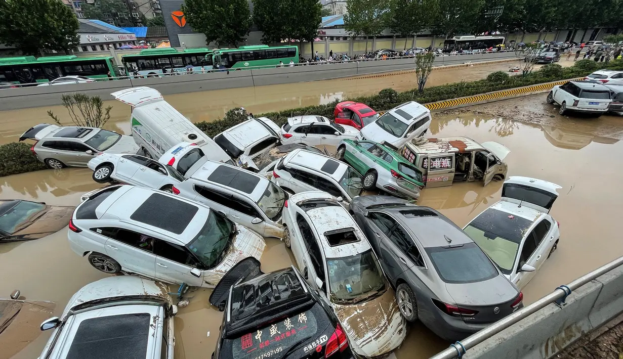 Mobil-mobil terendam banjir setelah hujan lebat melanda kota Zhengzhou di provinsi Henan tengah China (21/7/2021). Luapan sungai menggenangi jalan-jalan dan membuat kendaraan terbawa arus setelah curah hujan 200 mm turun dalam satu jam. (AFP/STR)