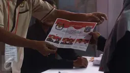 Petugas KPPS memberikan surat suara ke warga saat pemilihan Suara Ulang di TPS 29, Jakarta, Minggu (19/2). Bawaslu telah menemukan adanya pelanggaran saat berlangsungnya pemungutan suara di TPS 29 pada 15 Februari 2017 lalu. (Liputan6.com/Helmi Afandi)
