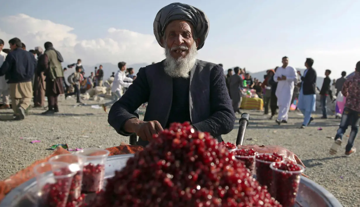 Seorang pria menjual buah delima di taman umum selama perayaan Nowruz, Tahun Baru Persia, di Kabul, Afghanistan, (21/3). Nowruz dirayakan pada hari pertama musim semi di negara-negara termasuk Afghanistan, Tajikistan, dan Iran. (AP Photo/Massoud Hossaini)