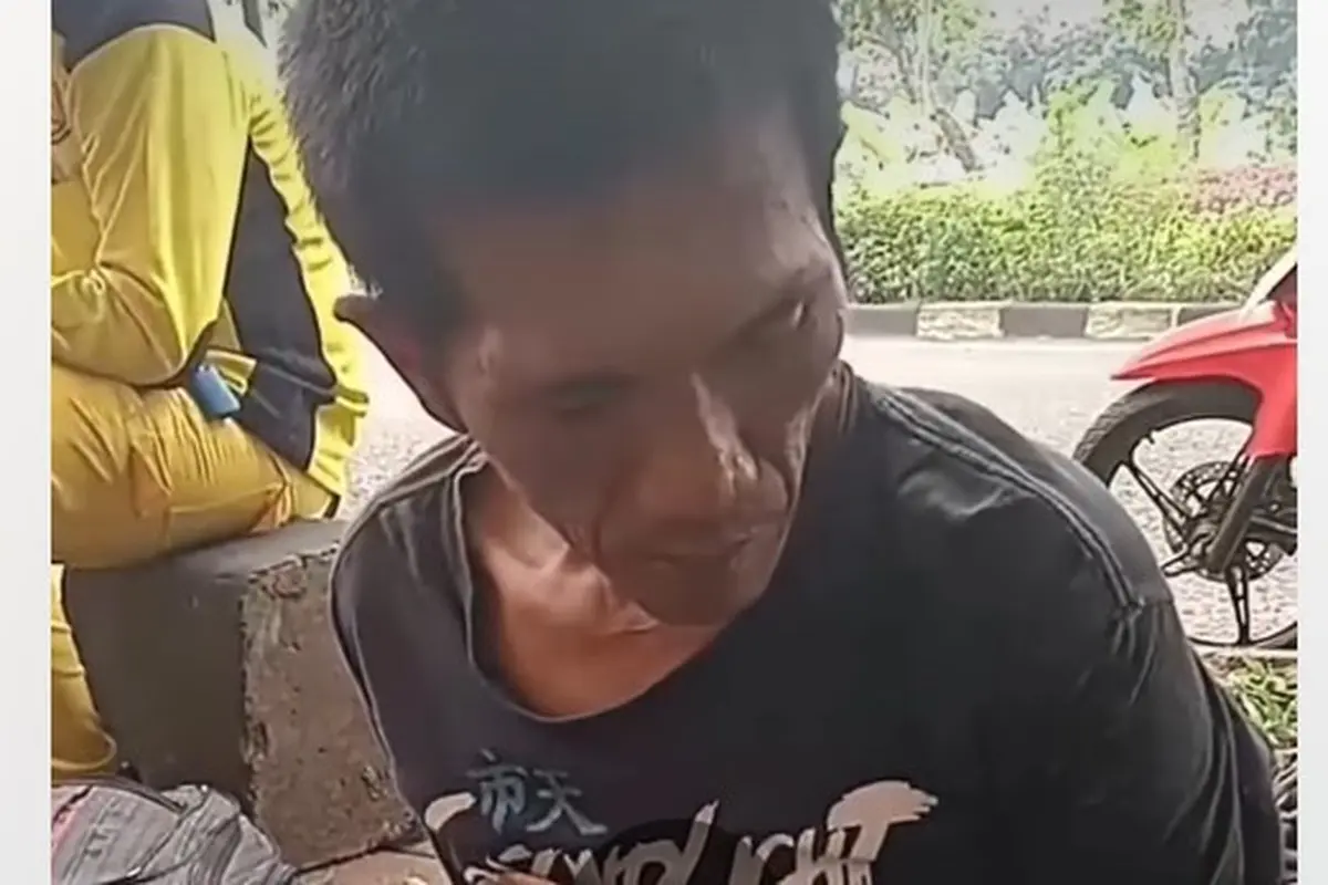 Seorang pria berkaos hitam tertunduk lesu saat diinterogasi di trotoar Jalan Basuki Rahmat, Kelurahan Cipinang Muara, Kecamatan Jatinegara. (Dok. Tangkapan Layar Instagram @jabodetabek24info)