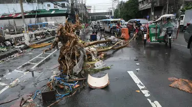 Pengendara kendaraan bermotor melewati batang pohon yang tergeletak di salah satu jalan di Manila, Filipina pada 25 Juli 2024. (TED ALJIBE/AFP)