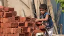 Dua orang anak mengangkat batu batu di sebuah bangunan New Delhi, India, Minggu (19/11). Setengah dari seluruh pekerja anak-anak melakukan pekerjaan yang dianggap berbahaya serta tidak ada kontrak kerja dan jaminan sosial. (DOMINIQUE FAGET)
