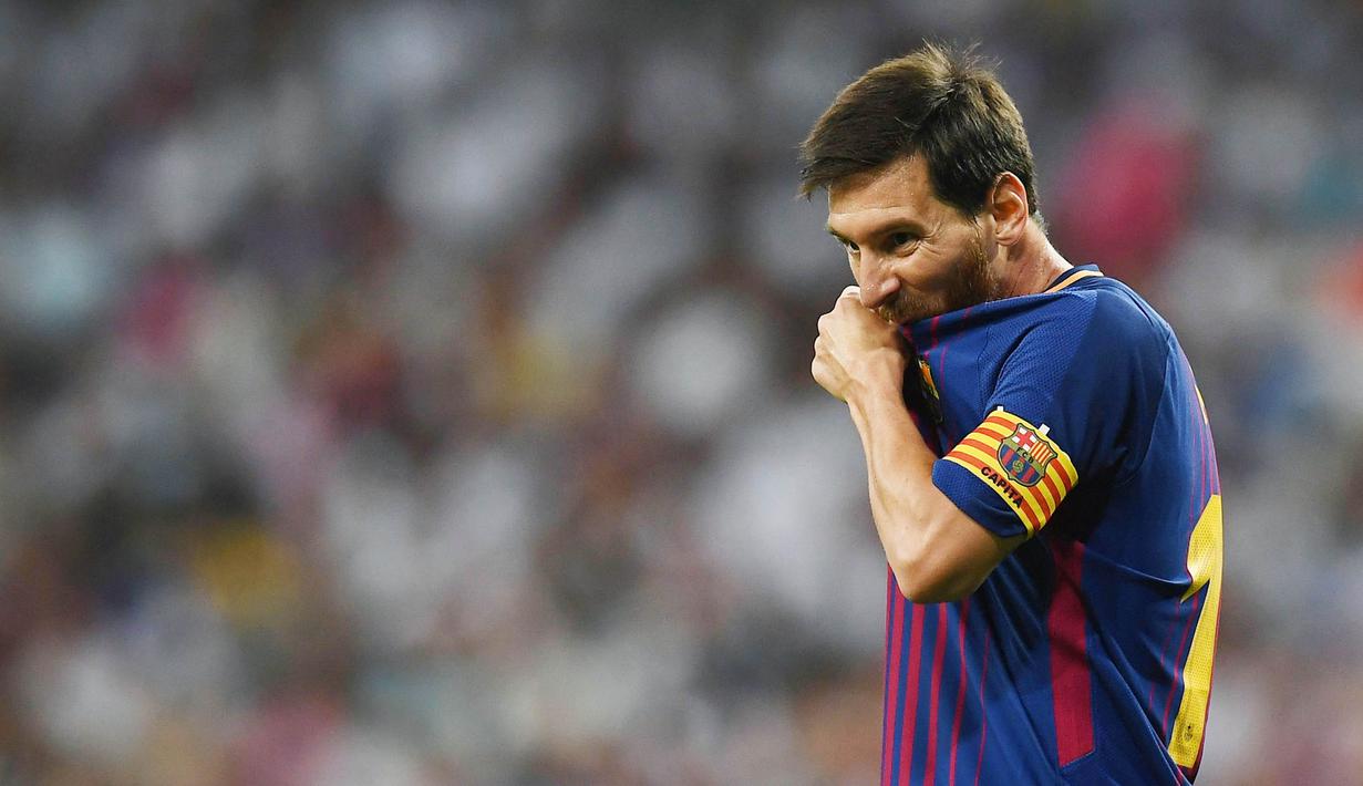 Striker Barcelona, Lionel Messi, meluapkan kekecewaanya dengan menggigit baju usai takluk dari Real Madrid pada laga Piala Super Spanyol 2017 di Stadion Santiago Bernabeu, Rabu (16/8/2017). Real Madrid menang 2-0 atas Barcelona. (AFP/Gabriel Bouys)
