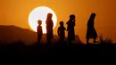 Anak-anak berlatar belakang matahari terbenam bermain di puncak bukit di pinggiran Islamabad, Pakistan pada 5 Juli 2020. (AP Photo / Anjum Naveed)