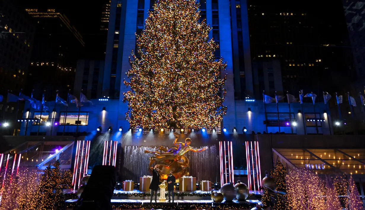Lebih dari 50.000 lampu menghiasi Pohon Natal Rockefeller Center setinggi 75 kaki pada upacara tahunan pencahayaan di New York, Rabu (2/11/2020). Upacara yang digelar pada masa pandemi COVID-19 ini mewajibkan pengunjung untuk memakai masker, pembatasan waktu, dan jaga jarak. (AP Photo/Craig Ruttle)
