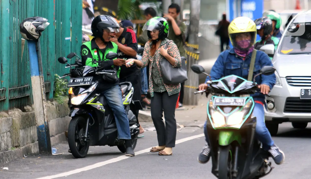 Penumpang membayar ongkos kepada pengemudi ojek online di Jakarta, Selasa (10/3/2020). Kementerian Perhubungan (Kemenhub) melalui Direktorat Jenderal Perhubungan Darat resmi menaikkan tarif batas atas dan tarif batas bawah ojek online. (Liputan6.com/Angga Yuniar)