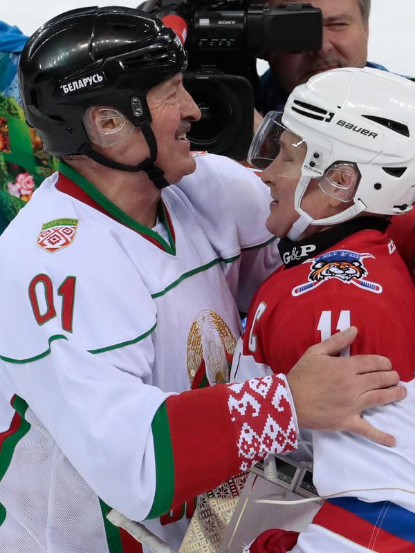 Presiden Rusia Vladimir Putin (kanan) dan Presiden Belarusia Alexander Lukashenko (kiri) berpelukan usai mengikuti pertandingan hoki es di Shayba Arena, Resor Laut Hitam Sochi, Rusia, (15/2). (Sergei Chirikov / Pool / AFP)