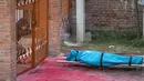 Seorang anggota keluarga berduka di samping mayat korban COVID-19 sebelum dikremasi di tepi Sungai Bagmati dekat kuil Pashupatinath di Kathmandu, Nepal (3/5/2021). Nepal juga membatasi pergerakan orang dan kendaraan serta menutup pasar, kantor dan sekolah. (AP Photo/Niranjan Shrestha)