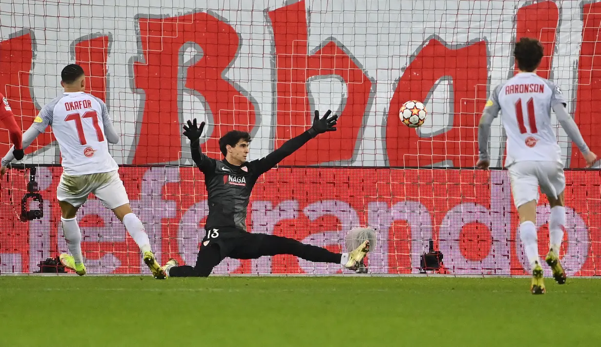 Gelandang Salzburg, Noah Okafor (kiri) mencetak gol melewati kiper Sevilla, Bono (tengah) dalam pertandingan Grup G Liga Champions di Salzburg, Austria, Kamis (9/12/2021). Kemenangan ini membuat RB Salzburg menempati posisi kedua klasemen dengan torehan 10 poin. (AFP/Joe Klamar)