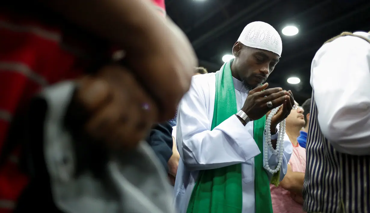 Seorang pria memanjatkan doa di depan jenazah Muhammad Ali yang akan disalatkan di Louisville, Kentucky, AS, Kamis (9/6). Ribuan orang hadir dalam salat jenazah almarhum legenda tinju dunia Muhammad Ali. (REUTERS/Lucy Nicholson)
