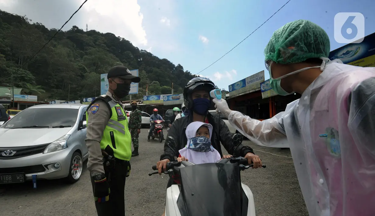 Petugas mengecek suhu tubuh pengendara saat penyekatan arus lalu lintas di Ciloto, Cianjur, Jawa Barat, Jumat (17/4/2020). Pemkab Cianjur melakukan pengecekan suhu tubuh dan penyemprotan disinfektan di titik keluar-masuk Cianjur untuk mencegah penyebaran COVID-19. (merdeka.com/Arie Basuki)