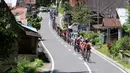 Pebalap melintasi perkampungan sepanjang etape ke-5 Tour de Singkarak dari Pantai Carocok-Painan menuju pantai Gondoriah-Pariaman, Sumatera Barart. (Bola.com/Nicklas Hanoatubun)
