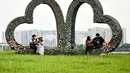 Seorang wanita berpose untuk foto di bangunan berbentuk hati di lapangan terbuka di sepanjang tepi sungai Merah di Hanoi (13/0/2020). (AFP/Manan Vatsyayana)