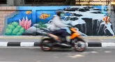 Pengendara sepeda motor melintas di samping mural bertema biota laut yang menghiasi dinding di kawasan Cideng, Jakarta, Rabu (29/11/2023). Mural dibuat guna memperindah sekaligus penataan kawasan Kelurahan Cideng, Jakarta Pusat. (Liputan6.com/Herman Zakharia)