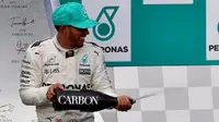 Pebalap Mercedes, Lewis Hamilton, melakukan selebrasi di podium setelah balapan F1 GP Malaysia di Sirkuit Sepang, Minggu (1/10/2017). (Bola.com/Twitter/F1)
